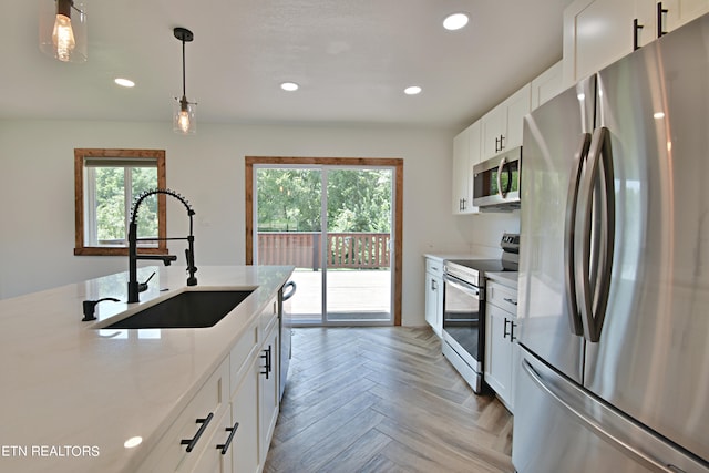 kitchen with appliances with stainless steel finishes, sink, a healthy amount of sunlight, and light parquet floors