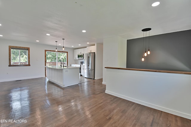 interior space featuring stainless steel appliances, a center island with sink, white cabinets, and dark hardwood / wood-style flooring