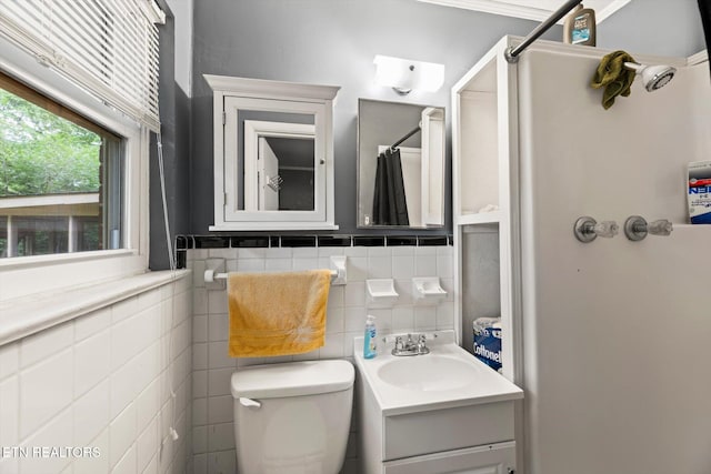 bathroom featuring vanity, toilet, tile walls, and walk in shower