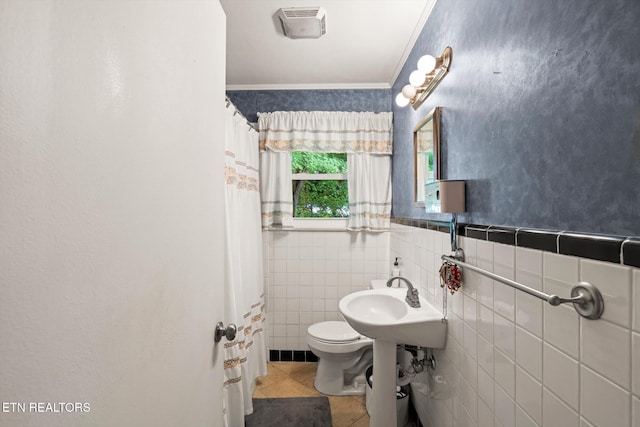 bathroom with a shower with shower curtain, toilet, tile patterned floors, tile walls, and crown molding