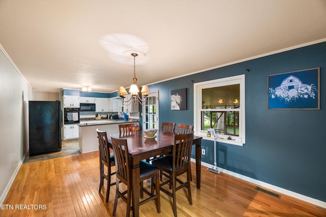 dining space featuring crown molding, a notable chandelier, and light hardwood / wood-style floors