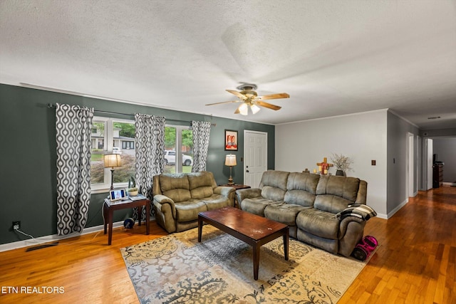 living room with a textured ceiling, crown molding, wood-type flooring, and ceiling fan