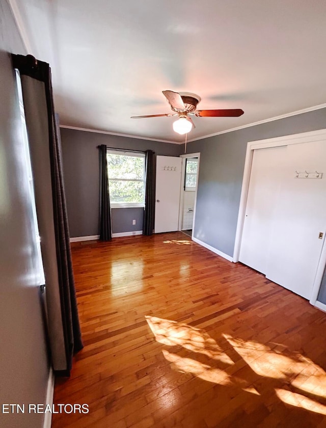 unfurnished bedroom featuring crown molding, hardwood / wood-style floors, a closet, and ceiling fan