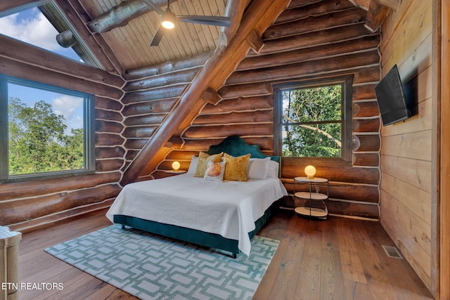 bedroom with lofted ceiling with beams, wood-type flooring, and rustic walls