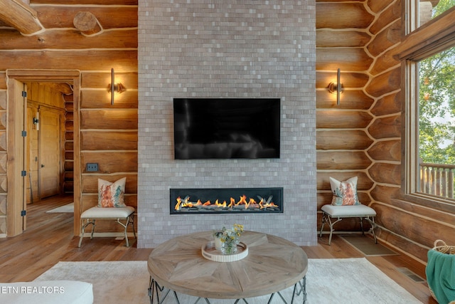 living room with light wood-type flooring, rustic walls, a large fireplace, and brick wall