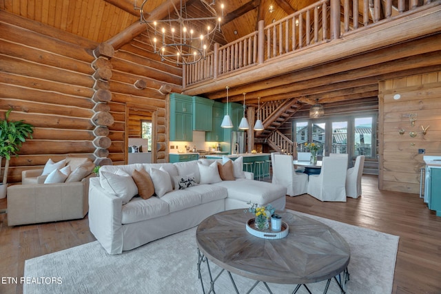 living room with light wood-type flooring, a towering ceiling, log walls, and a chandelier