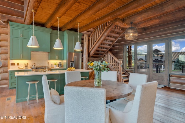 dining room featuring light wood-type flooring, beamed ceiling, log walls, and wooden ceiling