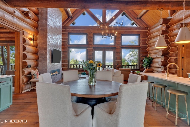 dining area with a wealth of natural light, high vaulted ceiling, and log walls