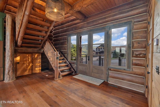 interior space featuring hardwood / wood-style floors, wood ceiling, rustic walls, and beamed ceiling