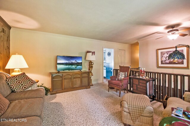 living room with carpet floors, ornamental molding, and ceiling fan