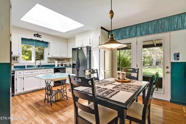 dining area with light hardwood / wood-style floors, sink, and a skylight