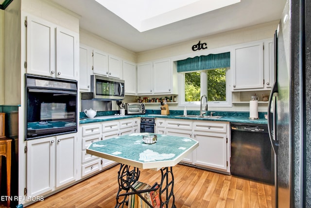 kitchen with white cabinets, sink, black appliances, and light hardwood / wood-style floors