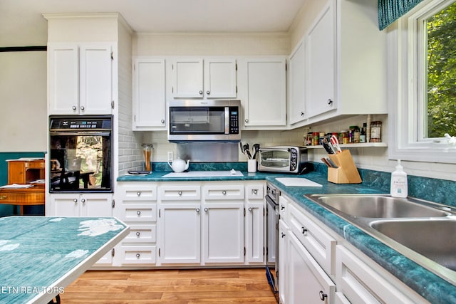 kitchen featuring white cabinetry, black oven, light hardwood / wood-style floors, backsplash, and stovetop