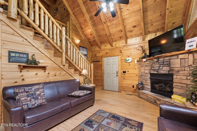 living room with light wood-type flooring, a fireplace, wooden walls, wood ceiling, and ceiling fan