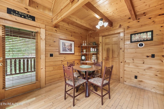 dining room featuring wooden walls, wooden ceiling, beamed ceiling, and light wood-type flooring