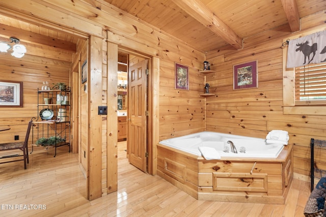 bathroom with beamed ceiling, wooden walls, a bathtub, wooden ceiling, and hardwood / wood-style flooring