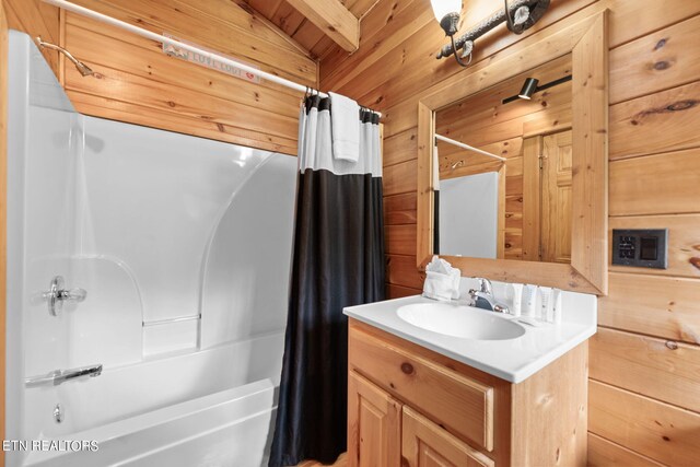 bathroom featuring wood walls, wooden ceiling, lofted ceiling with beams, vanity, and shower / bath combo