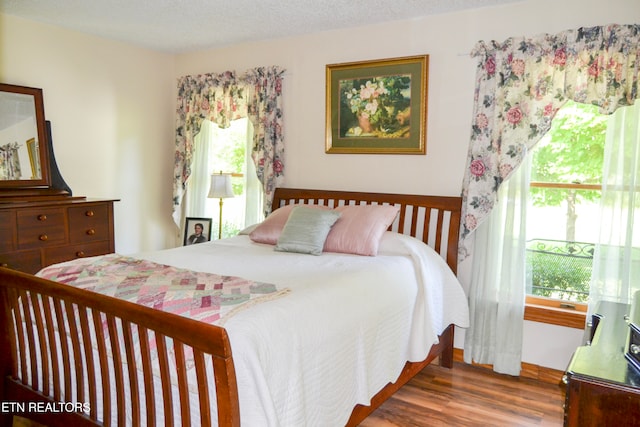 bedroom with a textured ceiling, hardwood / wood-style floors, and multiple windows