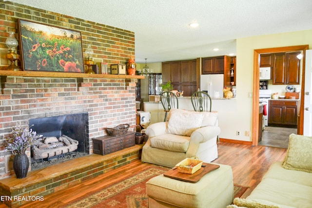 living room with a textured ceiling, brick wall, hardwood / wood-style flooring, and a brick fireplace