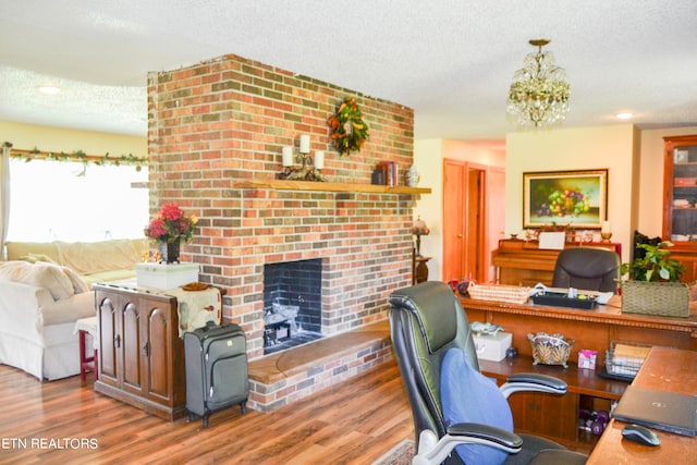 office featuring dark wood-type flooring, a notable chandelier, a textured ceiling, and a brick fireplace