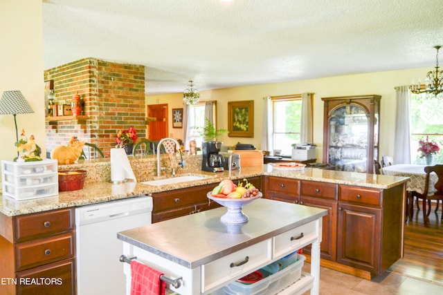 kitchen featuring sink, white dishwasher, a textured ceiling, a kitchen island, and light tile patterned floors