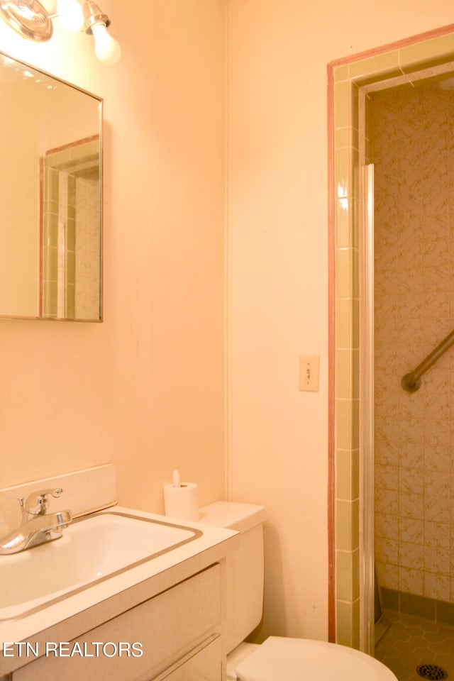 bathroom featuring toilet, a tile shower, and vanity