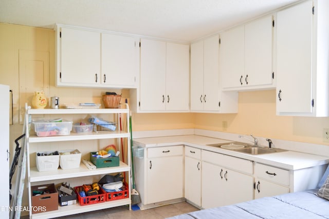 kitchen with light tile patterned floors, sink, and white cabinets