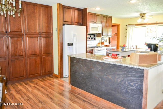 kitchen with white appliances, ceiling fan, light wood-type flooring, and light stone countertops