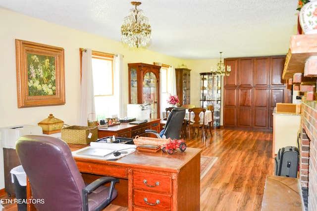 office featuring a fireplace, a notable chandelier, a textured ceiling, and light hardwood / wood-style flooring