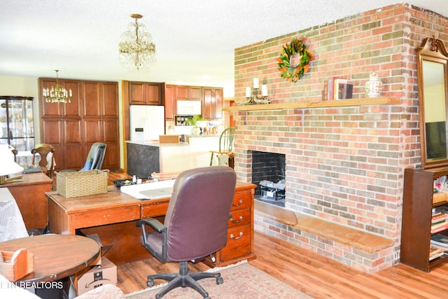 home office featuring a brick fireplace, light hardwood / wood-style flooring, a chandelier, a textured ceiling, and brick wall