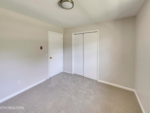 unfurnished bedroom with light colored carpet and a closet