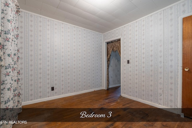 unfurnished room with hardwood / wood-style flooring and crown molding