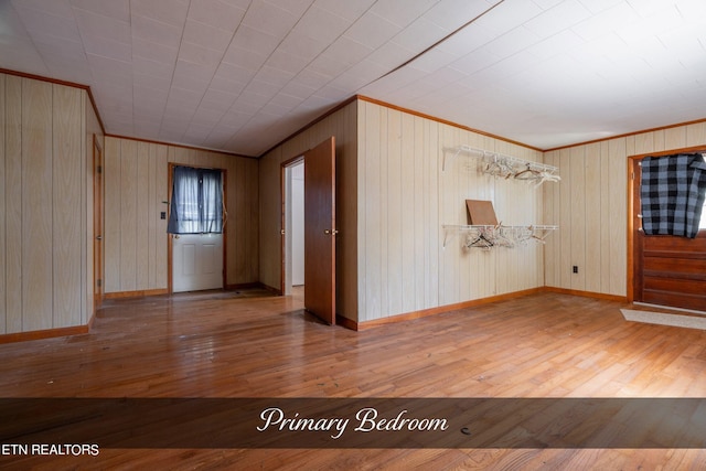 spare room with wooden walls, ornamental molding, and wood-type flooring