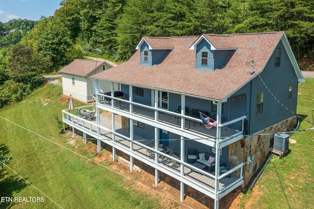 back of property with a deck, cooling unit, and a yard