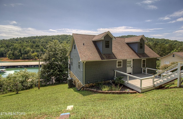 rear view of property with a deck, central air condition unit, and a lawn