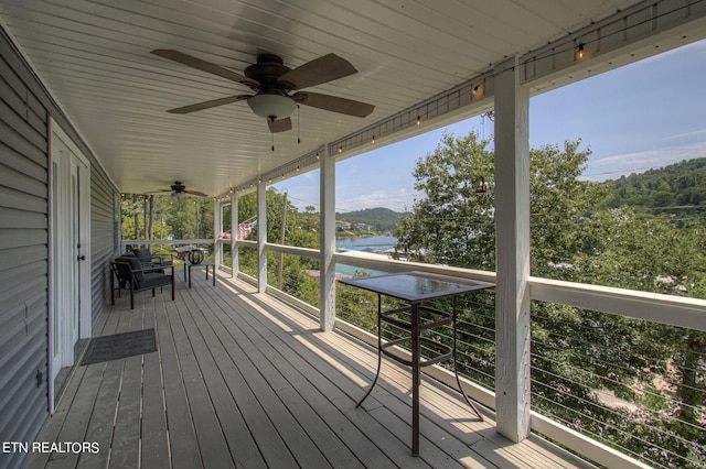 wooden terrace with ceiling fan and a water view