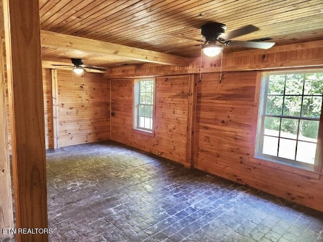 spare room with wooden walls, wood ceiling, a ceiling fan, and brick patterned floor