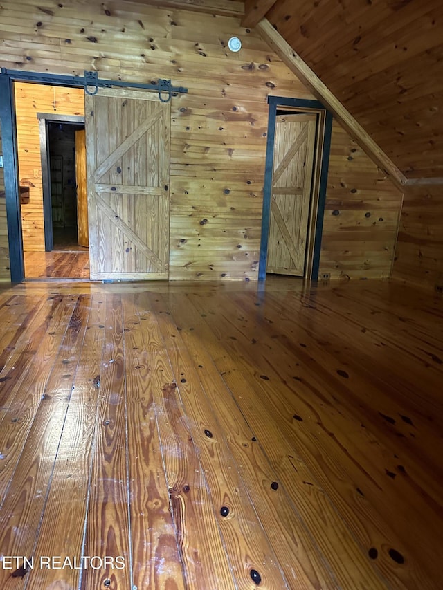 interior space featuring wooden ceiling, vaulted ceiling, wood walls, and hardwood / wood-style floors