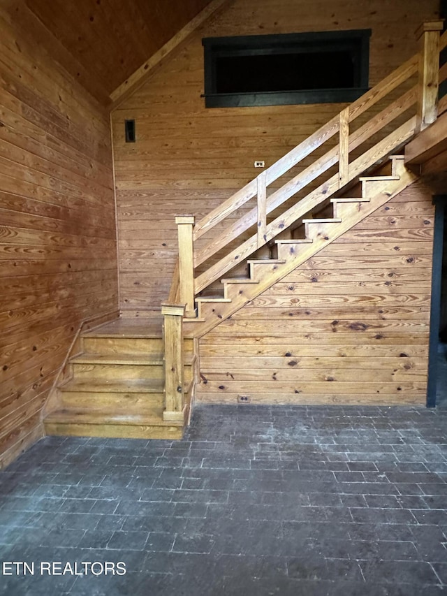 stairs featuring wooden walls, wooden ceiling, and lofted ceiling