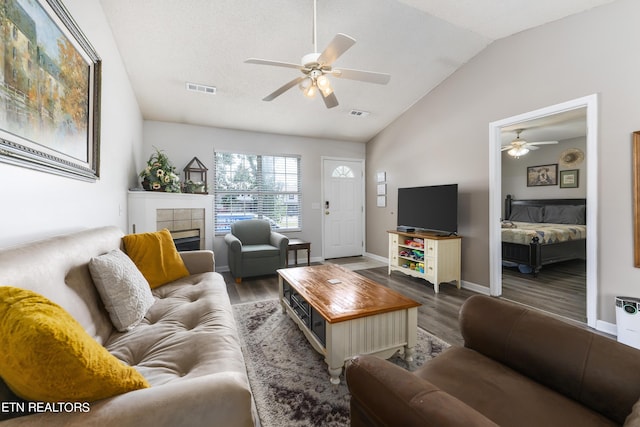 living room with ceiling fan, a fireplace, dark wood-type flooring, and vaulted ceiling