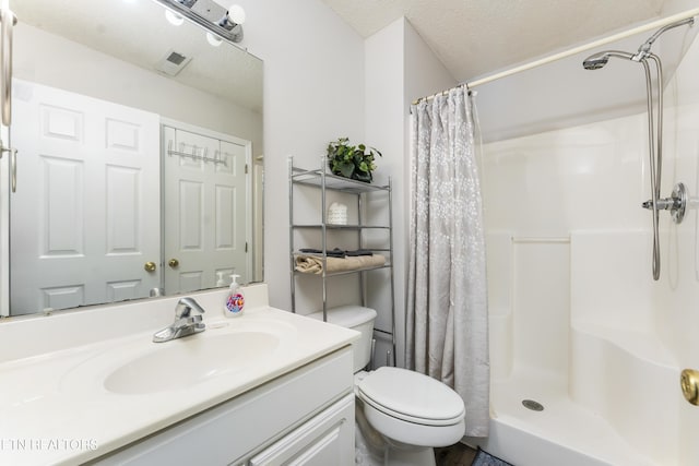 bathroom with vanity, a textured ceiling, toilet, and walk in shower