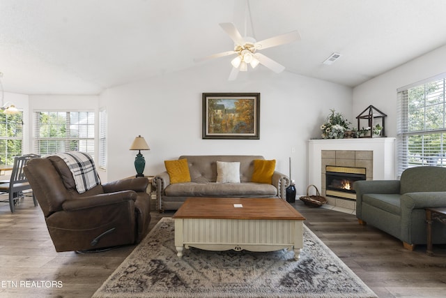 living room featuring dark hardwood / wood-style floors, ceiling fan, a tile fireplace, and vaulted ceiling