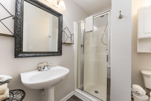 bathroom with a textured ceiling, sink, toilet, and walk in shower