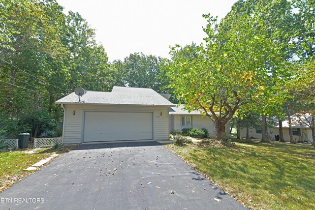 ranch-style home with a garage, aphalt driveway, and a front lawn