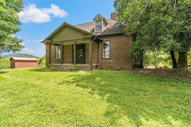 view of front of house with a porch, an outbuilding, a garage, and a front lawn