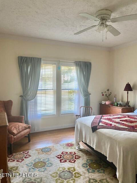 bedroom featuring ceiling fan, wood-type flooring, and a textured ceiling