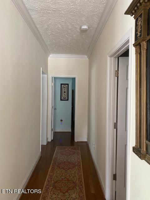 hallway featuring ornamental molding, a textured ceiling, and dark hardwood / wood-style floors