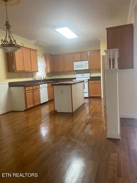 kitchen with hanging light fixtures, dark wood-type flooring, and white appliances