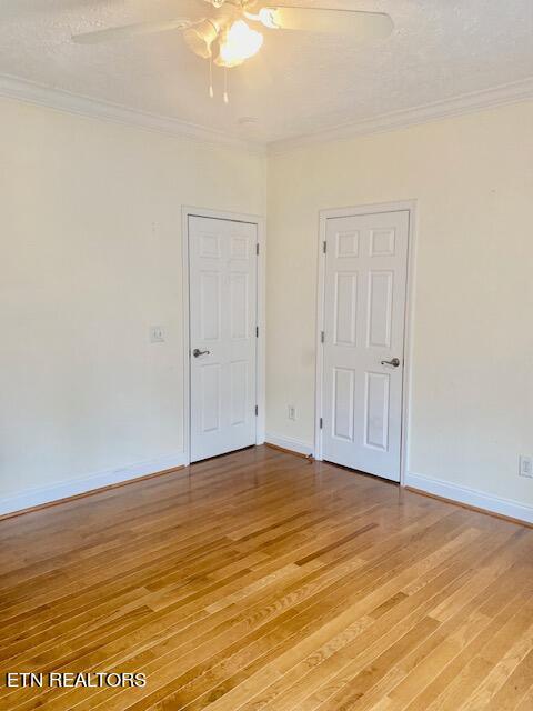 unfurnished room with ornamental molding, a textured ceiling, light wood-type flooring, and ceiling fan