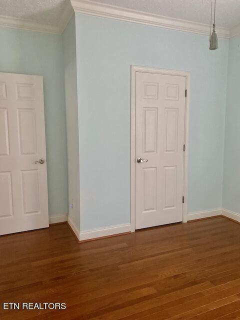 unfurnished room featuring ornamental molding, a textured ceiling, and dark hardwood / wood-style floors